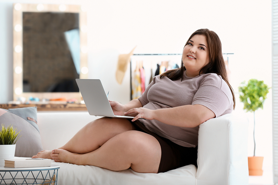 Beautiful overweight woman with laptop indoors.