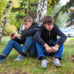 teenage boys sitting under tree